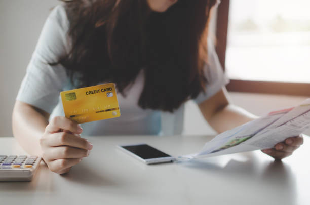 asian young woman holding credit card and analysis with family budget cost bills and mobile phone on desk in home office, plan money cost saving, investment, business finance and expenses concept mujer joven asiática que tiene tarjeta de crédito y análisis con facturas de costos del presupuesto familiar y teléfono móvil en el escritorio en la oficina del hogar, planificar el ahorro de costos de dinero, la inversión, las finanzas de negocios y
