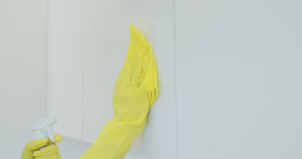 istock Woman's hand in a yellow rubber glove cleans the shiny surface of a modern plastic kitchen Cabinet with a cloth. The concept of spring cleaning and home work. 1173853112