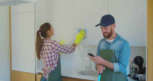 istock Man and woman as a professional cleaners in uniiform having fun during the work on the kitchen. 1173881105