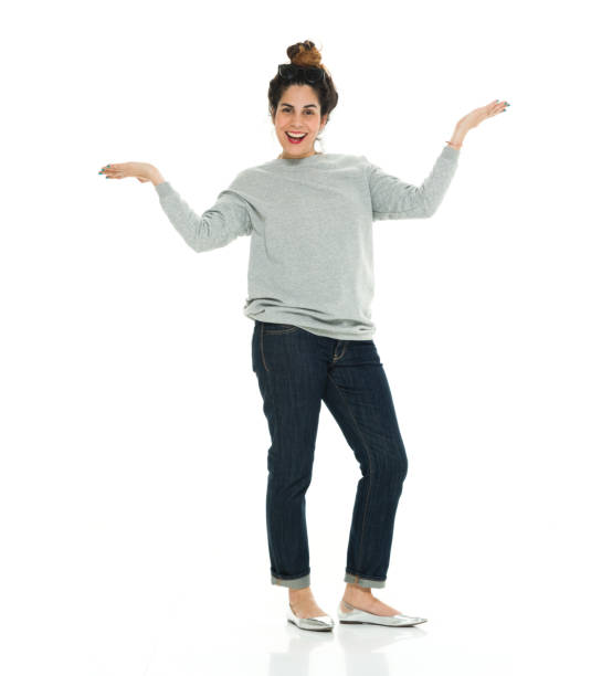 full length of 30-39 years old adult beautiful puerto rican ethnicity / latin american and hispanic ethnicity female / young women / one young woman only presenter standing in front of white background wearing sweater / jeans / cool attitude - puerto rican ethnicity women smiling cheerful imagens e fotografias de stock