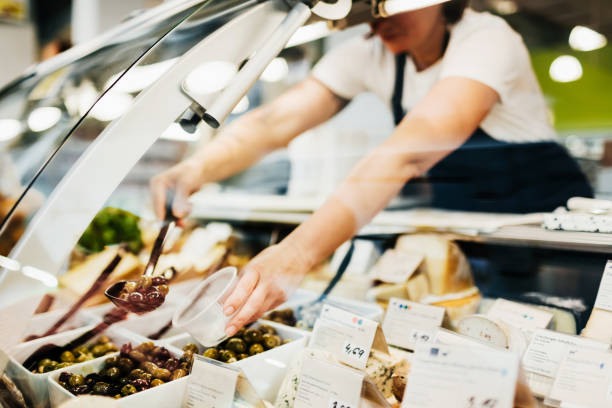 close up of supermarket clerk filling cup mit oliven - feinkostgeschäft stock-fotos und bilder