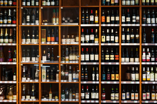 Large Cabinet With Many Bottles Of Wine At Supermarket A large wooden cabinet filled with many different kinds of bottles of wine at a supermarket. alcohol shop stock pictures, royalty-free photos & images