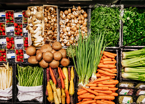 An aerial view of various vegetables, including mushrooms, carrots and asparagus at a local supermarket.