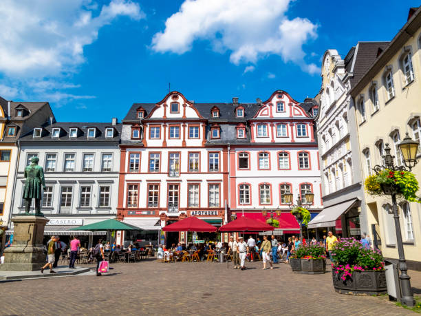Koblenz, Germany - August 09, 2013: The beautiful sunlit Jesuit Square with tourists and the statue of the Koblenz physiologist and anatomist Johannes Mueller, erected in 1899