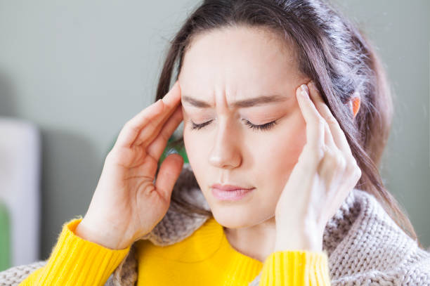 istock Young woman with headache sitting on sofa 1173896769