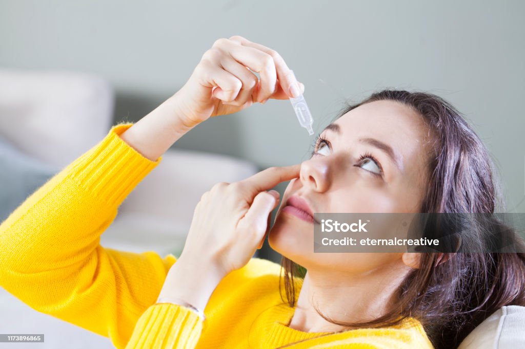 Closeup view of young woman applying eye drop, artificial tears. Young woman uses eye drops for eye treatment. Redness, Dry Eyes, Allergy and Eye Itching Eye Stock Photo