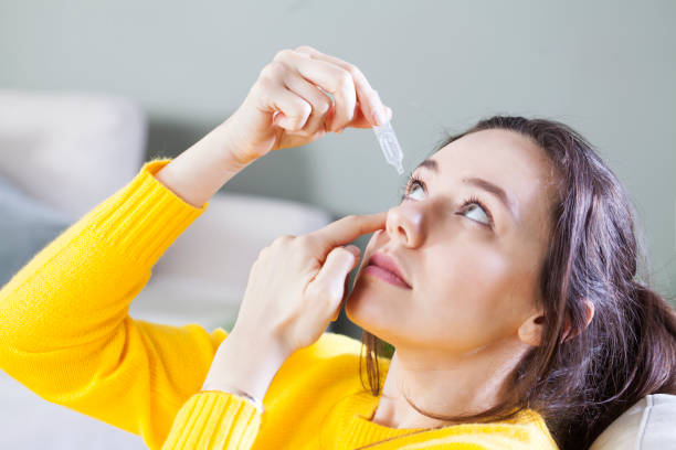 Closeup view of young woman applying eye drop, artificial tears. stock photo