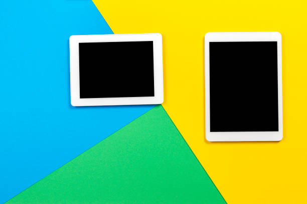 istock Two digital tablet computers on light blue, green and yellow background. Top view 1173896928