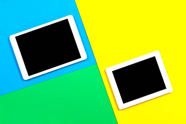 istock Two digital tablet computers on light blue, green and yellow background. Top view 1173897526