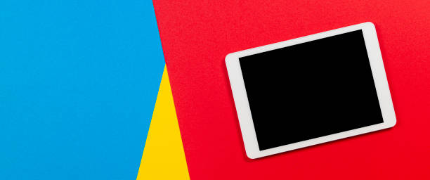 istock Digital tablet computer on red, yellow and light blue background. Top view 1173897600
