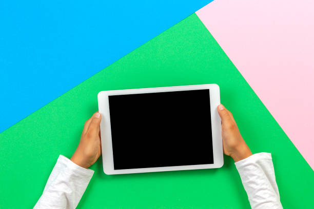 istock Kid hands with tablet computer on pastel pink, blue and green background 1173897713