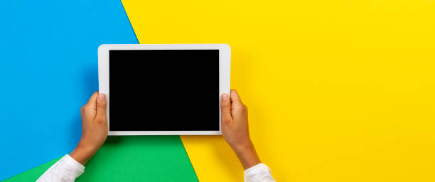 istock Kid hands with tablet computer on yellow, blue and green background 1173897740