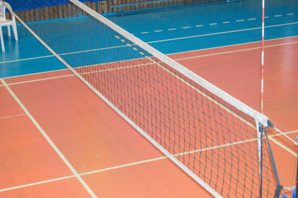 Empty gym with a stretched net for volleyball, against the background of orange and blue floor. Space for text. The concept of active sports, Hobbies stock photo