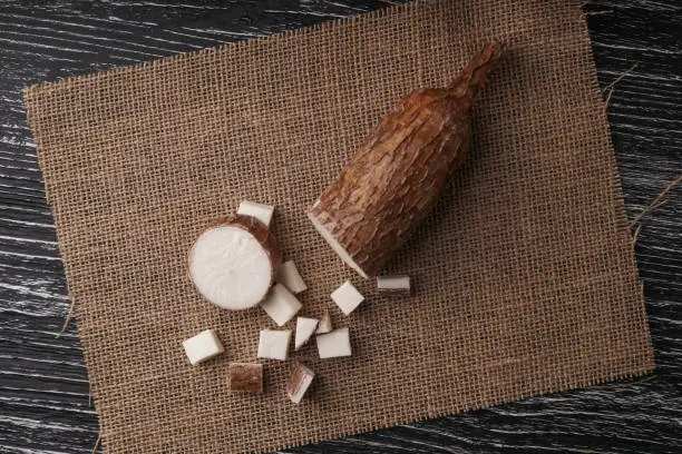 Sliced yucca root on a sackcloth on a black wooden table. Natural healthy ingredients