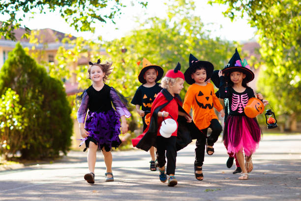 Kids trick or treat. Halloween fun for children. Child in Halloween costume. Mixed race Asian and Caucasian kids trick or treat on suburban street. Little boy and girl with pumpkin lantern and candy bucket. Baby in witch hat. Autumn holiday fun. trick or treat photos stock pictures, royalty-free photos & images