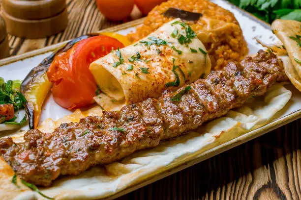 lula kebab spicy with vegetables in Turkish on the board