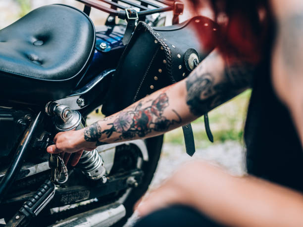 redhair женщина фиксации ее велосипед - motorcycle women tattoo sensuality стоковые фото и изображения