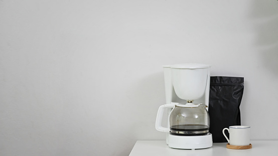 Coffee machine, coffee mug and black bag on copy space table.