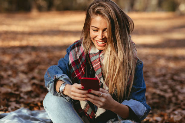 istock Young woman in the park using smartphone and smiling 1173909856