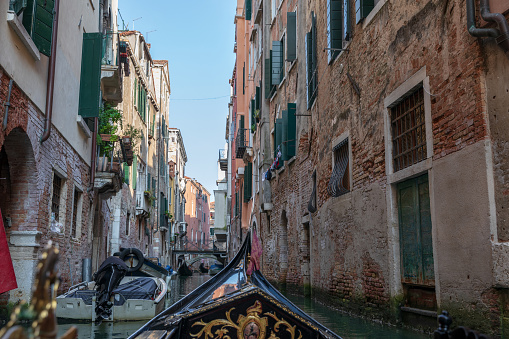 Venice, Italy - July 2, 2018: Panoramic view of Venice narrow canal with historical buildings from other gondola. Summer sunny day and sunset sky