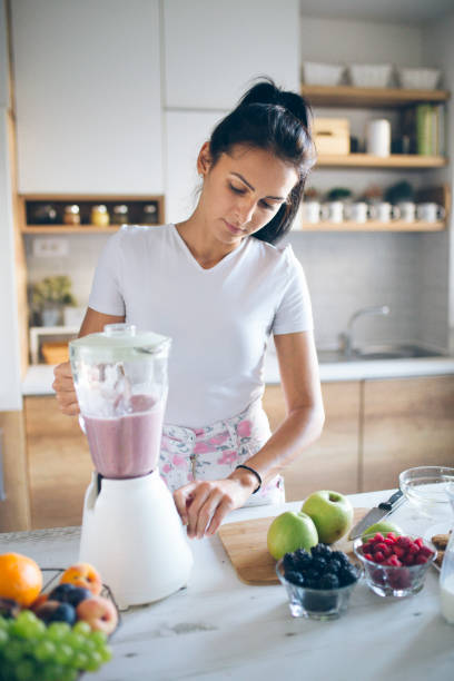 istock Smiling woman making smoothie 1173915393