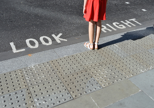 Pedestrian standing next to typical road crossing sign in London