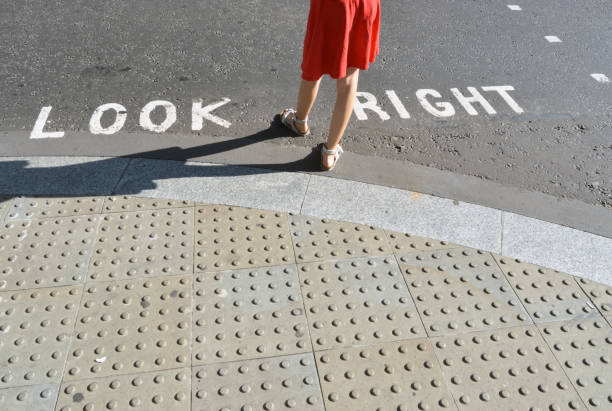 Pedestrian standing next to typical road crossing sign in London
