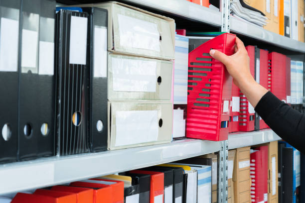 istock Mans hand picking a blank blind folder with files from the shelf. Archival, stacks of documents at the office or library 1173917463
