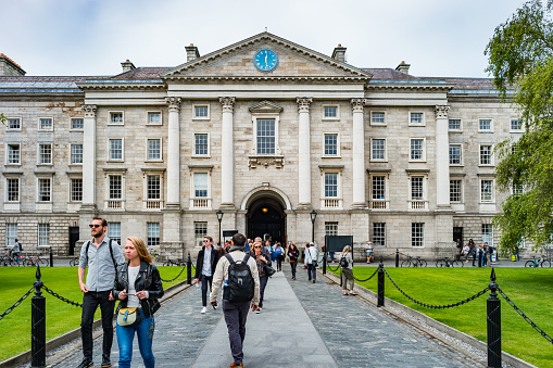 Pedestrians walk on Parliament Square on the Trinity College campus in downtown Dublin Ireland on a cloudy day.