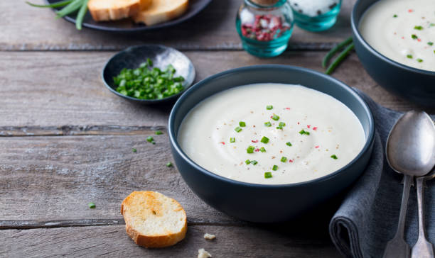 cauliflower and potato cream soup with green onion in a bowl on grey wooden background. copy space. - cauliflower vegetable portion cabbage imagens e fotografias de stock