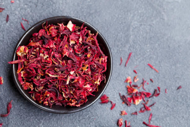 istock Hibiscus flower tea in black bowl on grey stone background. Copy space. Top view. 1173921750