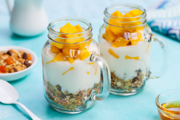 istock Fresh mango fruit with yogurt and granola in jars. Blue stone background. Close up. 1173923710