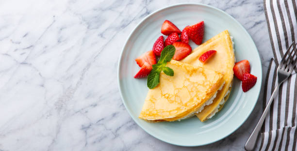 istock Crepes, thin pancakes with cream cheese, strawberries. Marble background. Top view. Copy space. 1173924689