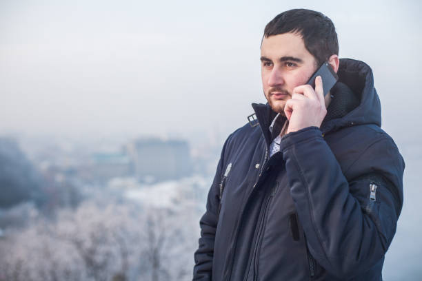 istock Man using smart phone outdoors against winter cityscape 1173926160
