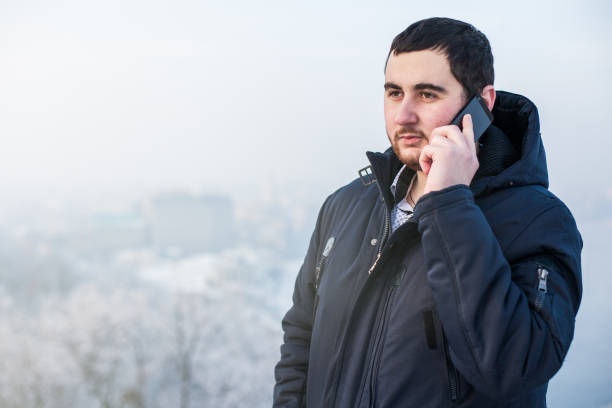 istock Man using smart phone outdoors against winter cityscape 1173926190