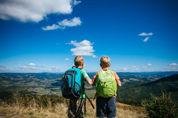 istock Little boys with backpack standing on top of mountain 1173926323