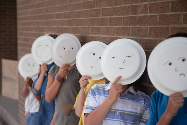 Confused elementary school child on the first day of school A group of children are lined up in a row in from of a brick wall. They bear different facial expressions, showing a range of emotions. school exclusion stock pictures, royalty-free photos & images