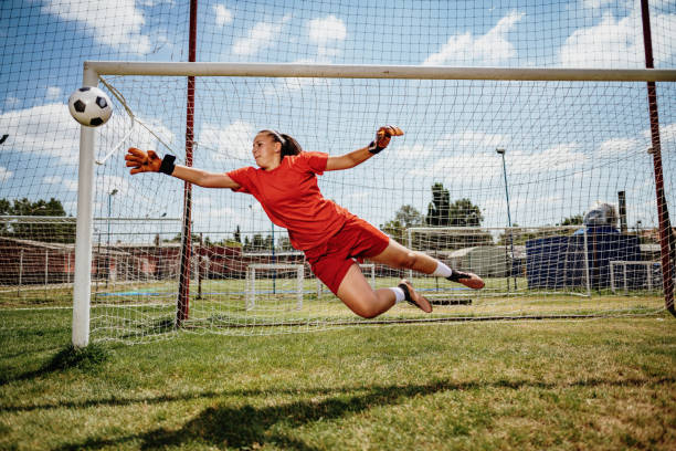 coup de pied de pénalité de football avec le gardien de but féminin de l'adolescence - fitness goal photos et images de collection