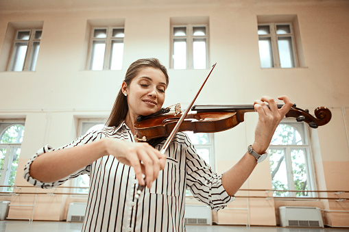 Woman playing violin near window