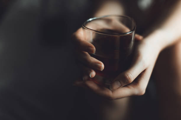 woman holds glass with whiskey. alcohol cocktail in glass. woman's alcoholism, alcohol addict concept stock photo