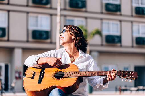 Mid adult woman playing acoustic guitar
