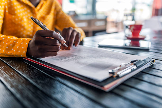 She's got month end reporting down to a fine art Close-up Of Businesswoman's Hand Signing On Papers Over Desk while sitting during the day. Filling out an important form. American woman working at home. Focus on hand. Close up. filling out stock pictures, royalty-free photos & images