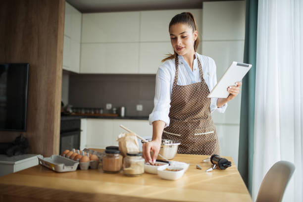 istock Young woman using tablet in kitchen where read cake recipe 1173951713