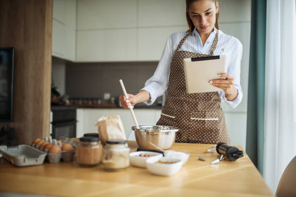 istock Young woman using tablet in kitchen where read cake recipe 1173951774