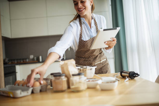 istock Young woman using tablet in kitchen where read cake recipe 1173952451