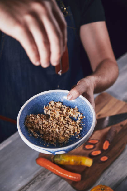istock Young chef in kitchen holding bowl with walnut and preparing dinner. Food concept. 1173952503