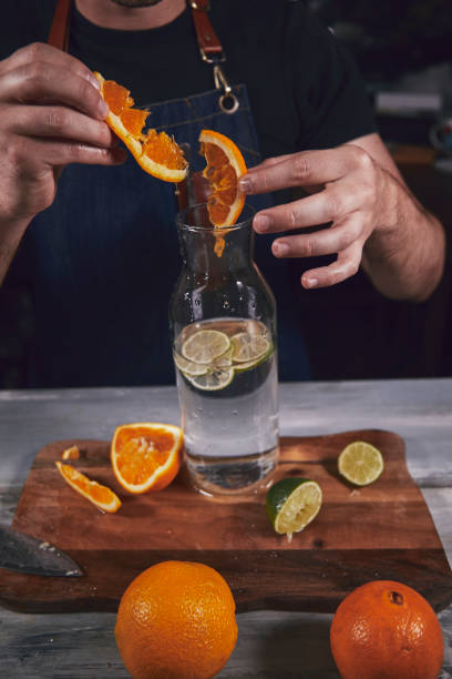 istock Young chef in kitchen squeeze orange and lime for juice. Food concept. 1173953390