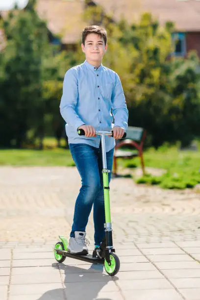 Photo of young teenage boy on scooter in park