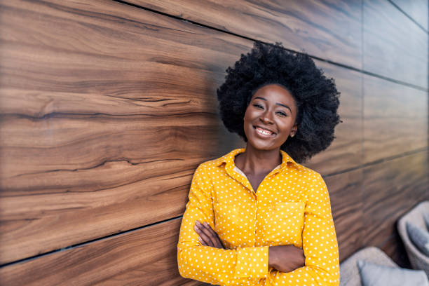 Portrait of smiling young african businesswoman. Cheerful young woman standing relaxed in her office, looking at camera and smiling.