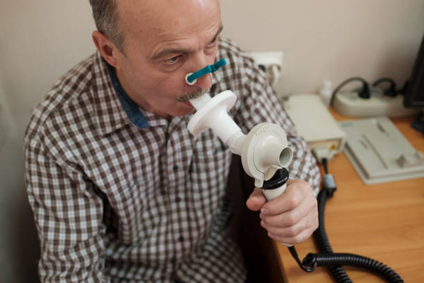 Senior hispanic man man testing breathing function by spirometry stock photo